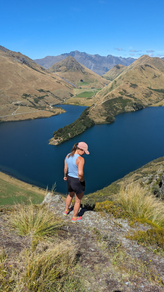 Carolyn standing on a mountain looking down at Moke Lake