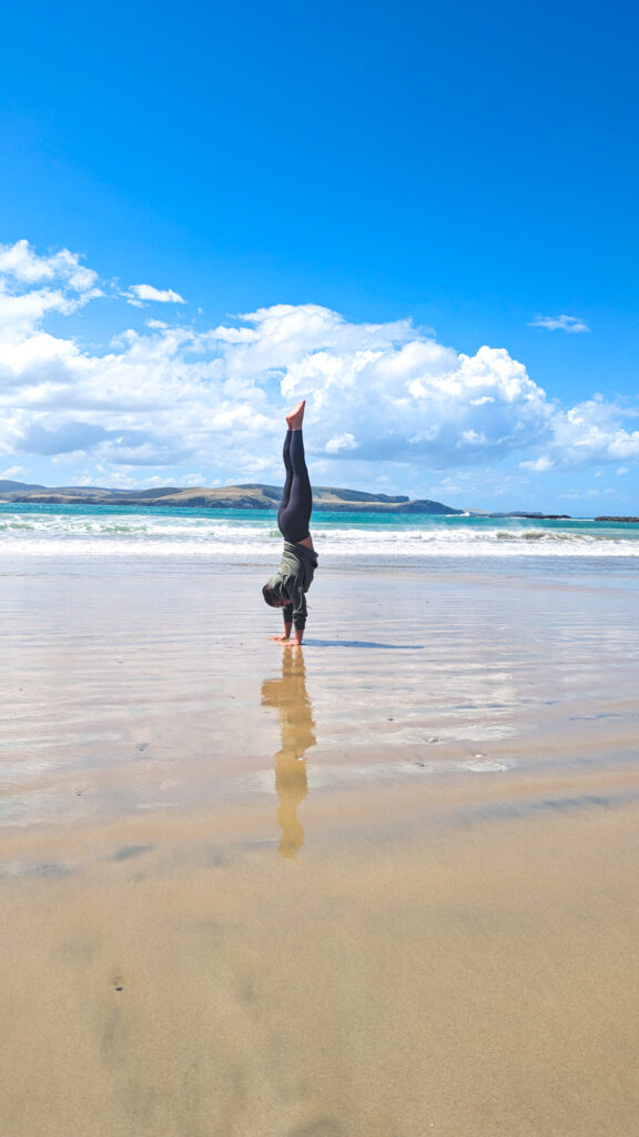 Carolyn doing a handstand on a beach in the Catlins